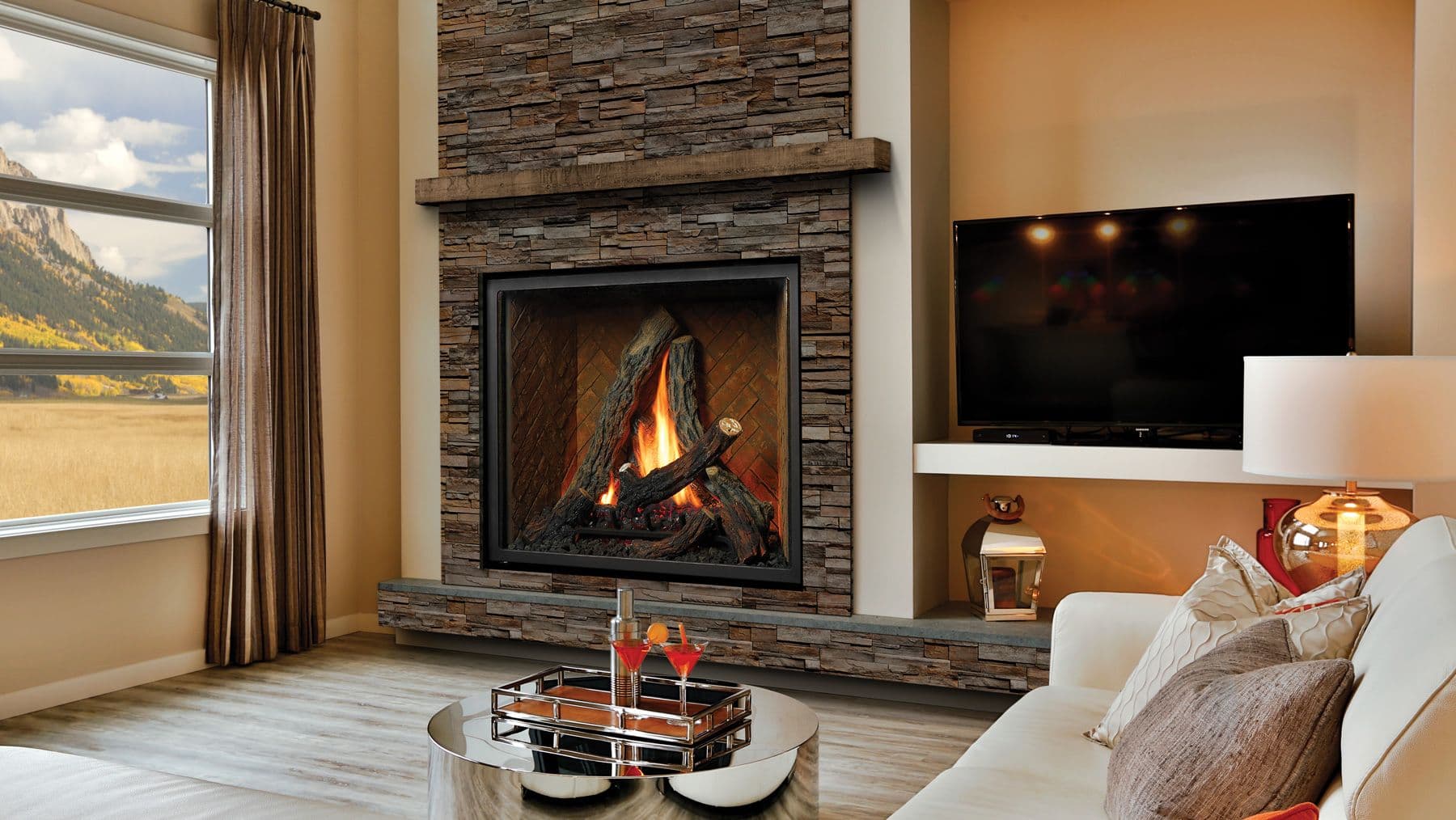 Cozy living room with a stone fireplace and crackling fire. A large window reveals a scenic mountain view. Modern decor with neutral tones.